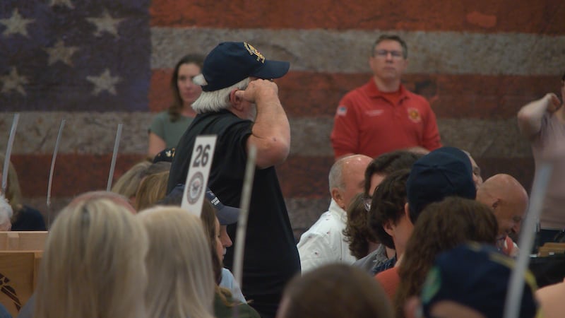 A Navy veteran salutes as The Gibson Girls sing the song for his branch, "Anchors Aweigh."