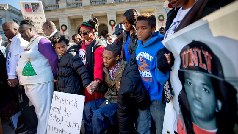 Demonstrators join hands in a moment of prayer during a "Who Killed K.J." rally in memory of...